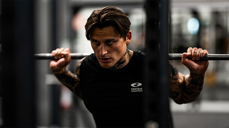 Bild på man med en skivstång på ryggen. Bild på man med en skivstång på ryggen.